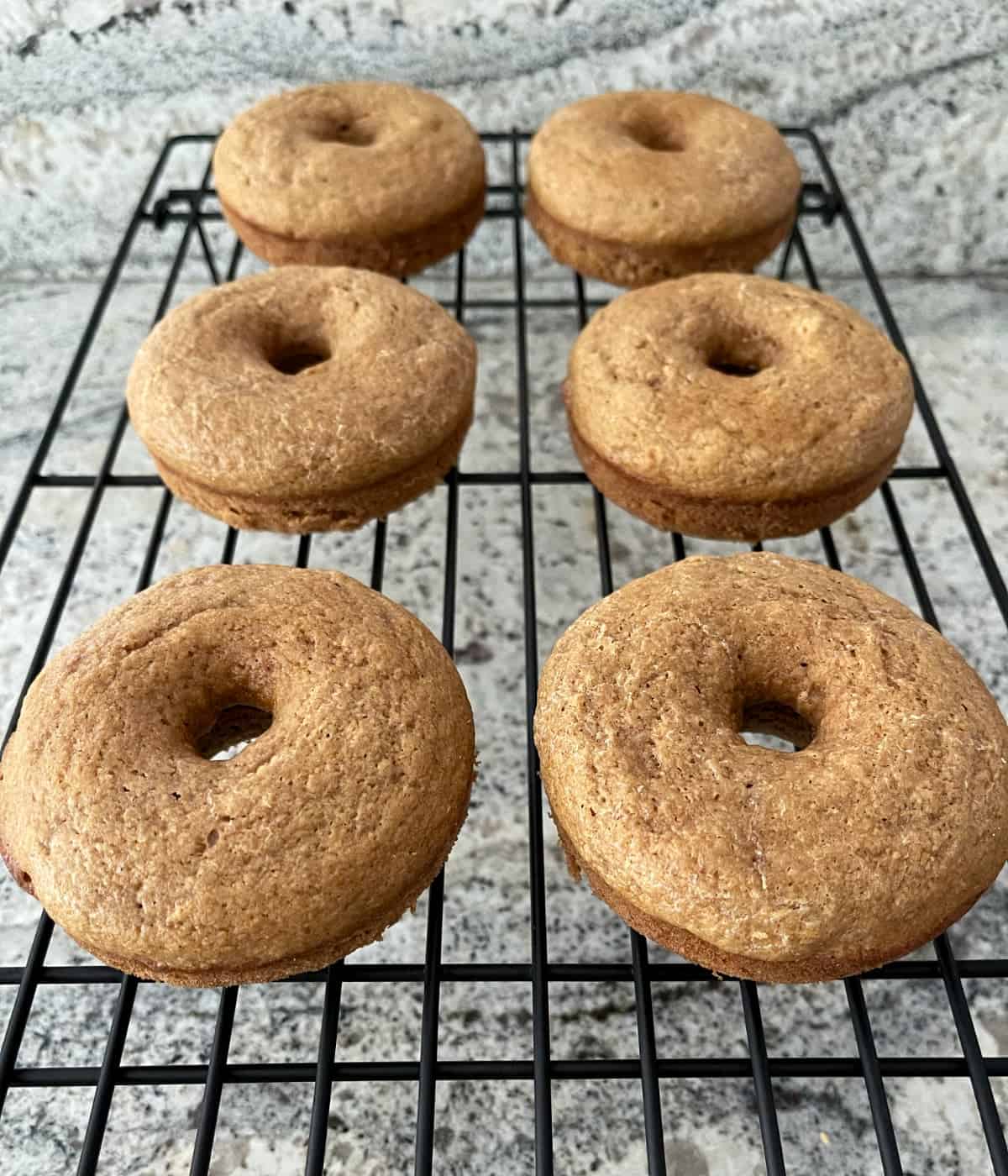 Baked whole wheat donuts cooling on wire rack.