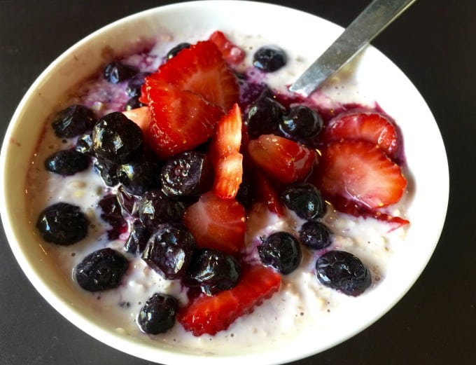 Close up of summer muesli with fresh blueberries and sliced strawberries in a white bowl