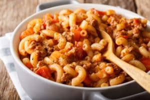 American Chop Suey (Hamburger Goulash with Elbow Macaroni), ground beef, tomatoes, tomato sauce and spices close-up in a white serving dish.