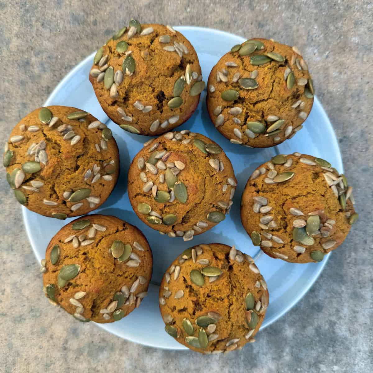 Fresh baked pumpkin muffins on round blue serving plate.