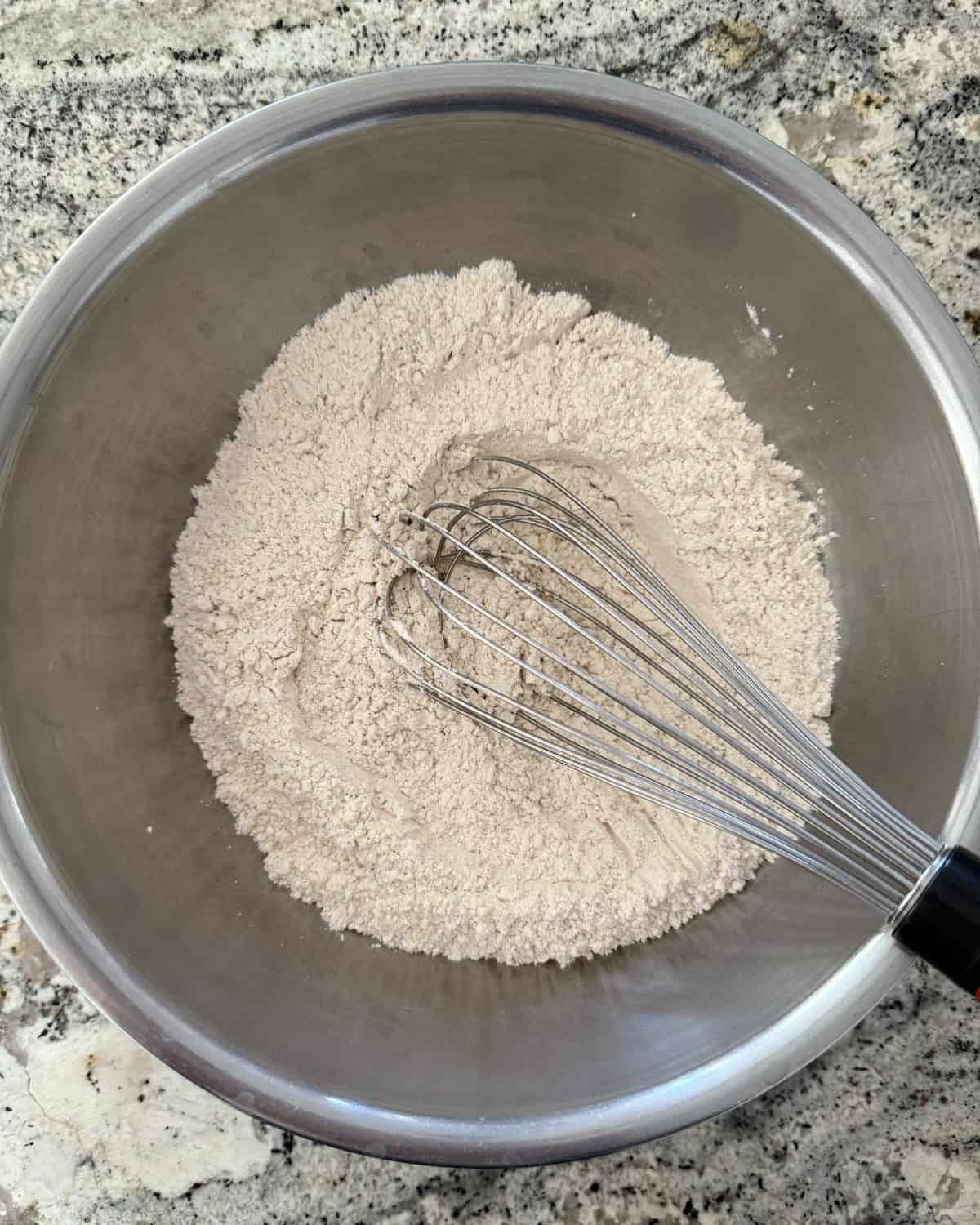 Whisking flour, baking powder, baking soda, salt, cinnamon, ginger, nutmeg and allspice in mixing bowl.
