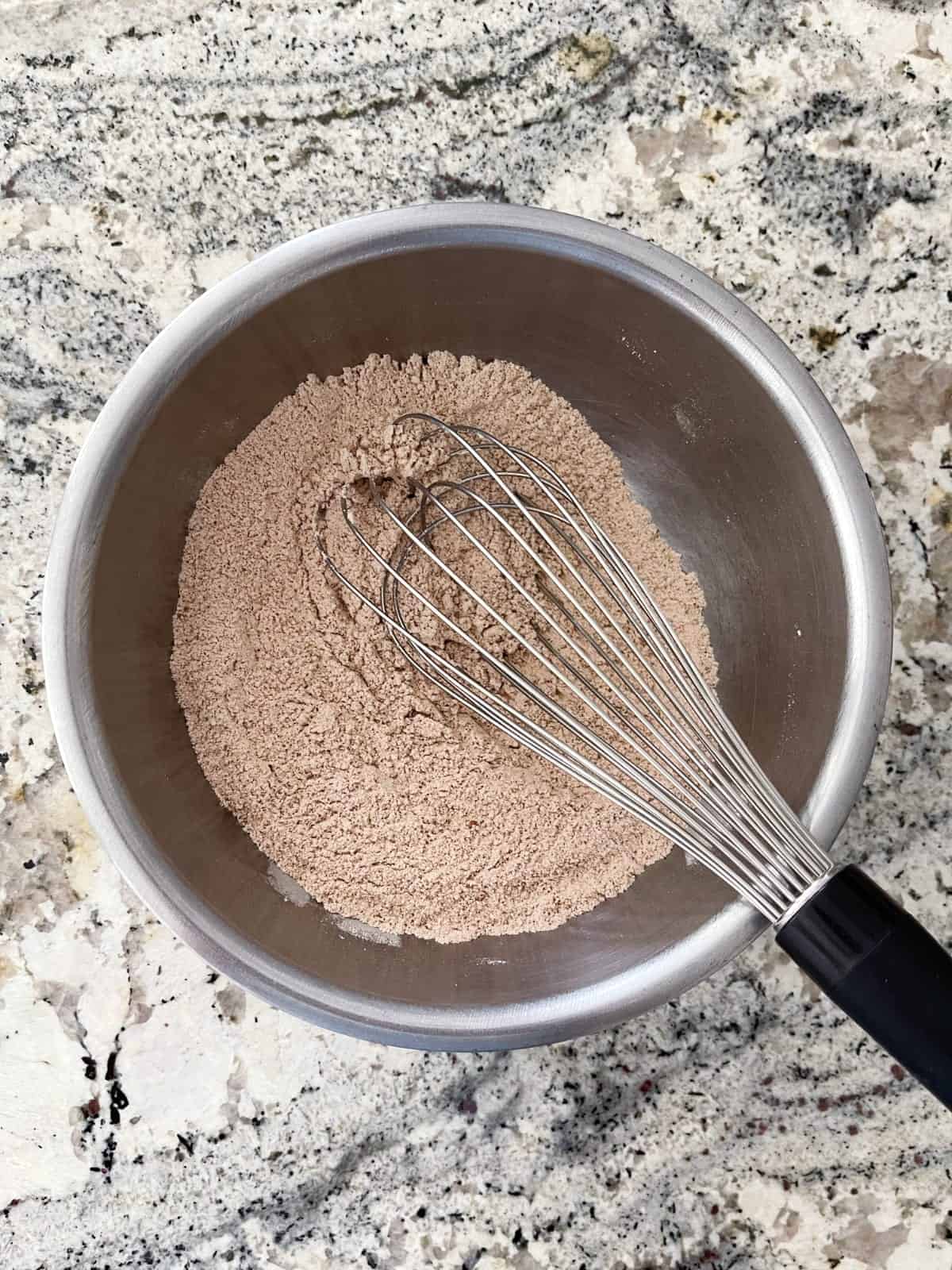 Whisking flour, baking powder, salt, coffee powder and cocoa powder in mixing bowl.