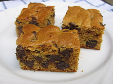 Three blonde brownies with chocolate chips on a white plate.