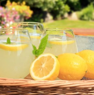 Basket with 3 glasses of fresh lemonade with lemons on the side
