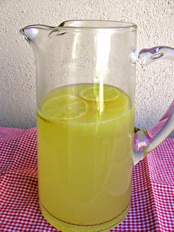 Pitcher of fresh lemonade on a small table with a red and white checkered tablecloth
