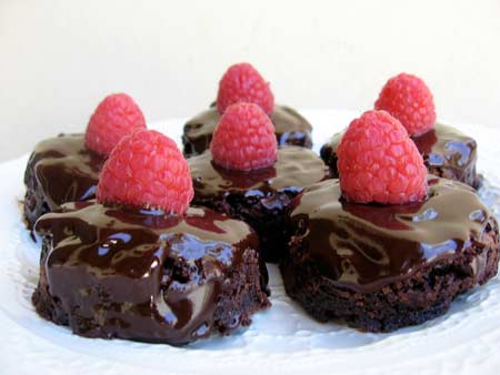 Plate of Seven Brownies Topped with Chocolate Ganache and a Fresh Raspberry