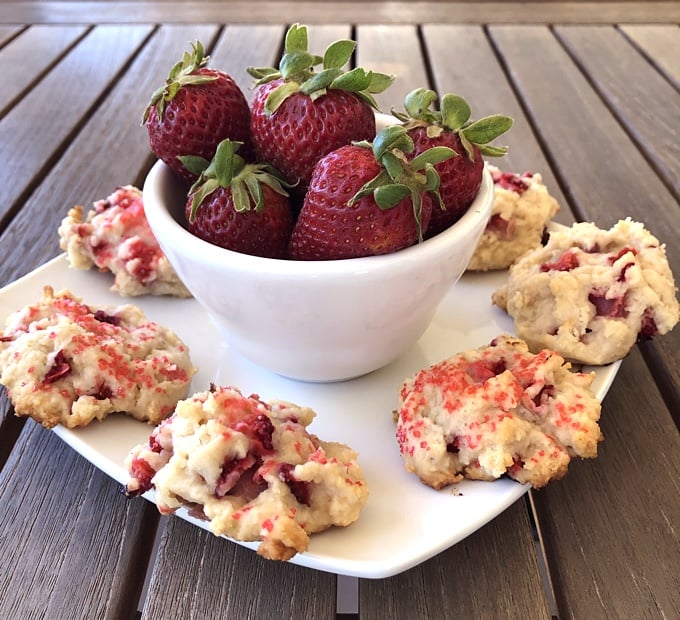 Plate with strawberry shortcake cookies and bowl of fresh strawberries