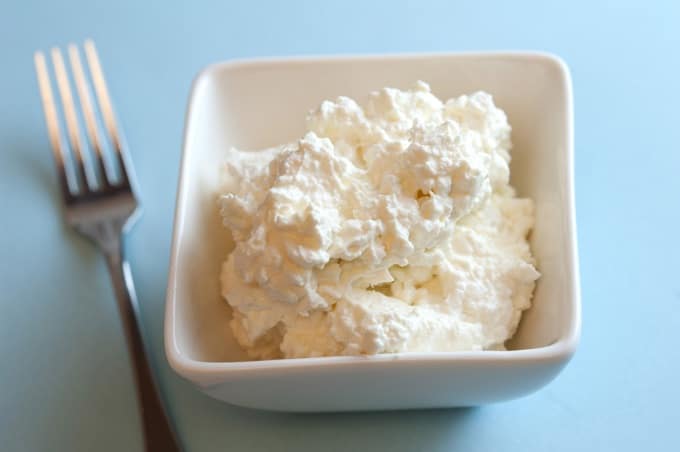 Dish of cottage cheese in a square white bowl with a fork