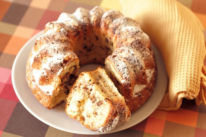 Banana bundt cake dusted with powdered sugar on serving plate.