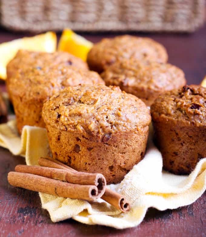 Healthy breakfast muffins on a yellow dish towel with cinnamon sticks.