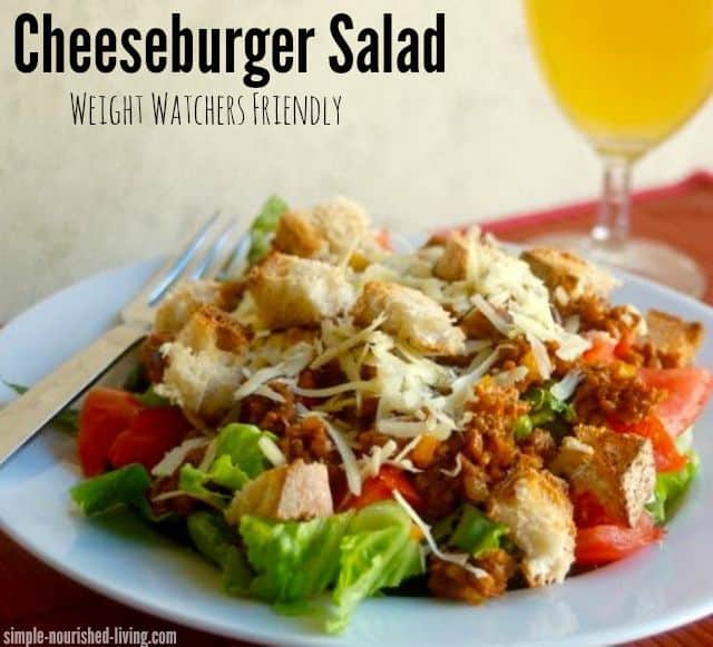 Cheeseburger Salad with croutons on white plate with iced tea alongside