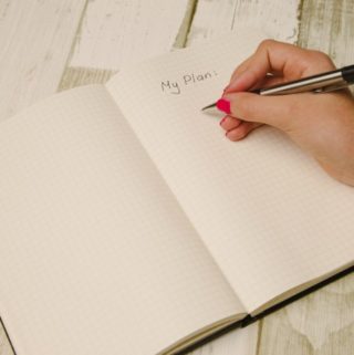hand holding pen writing in a planner