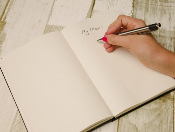 hand holding pen writing in a planner