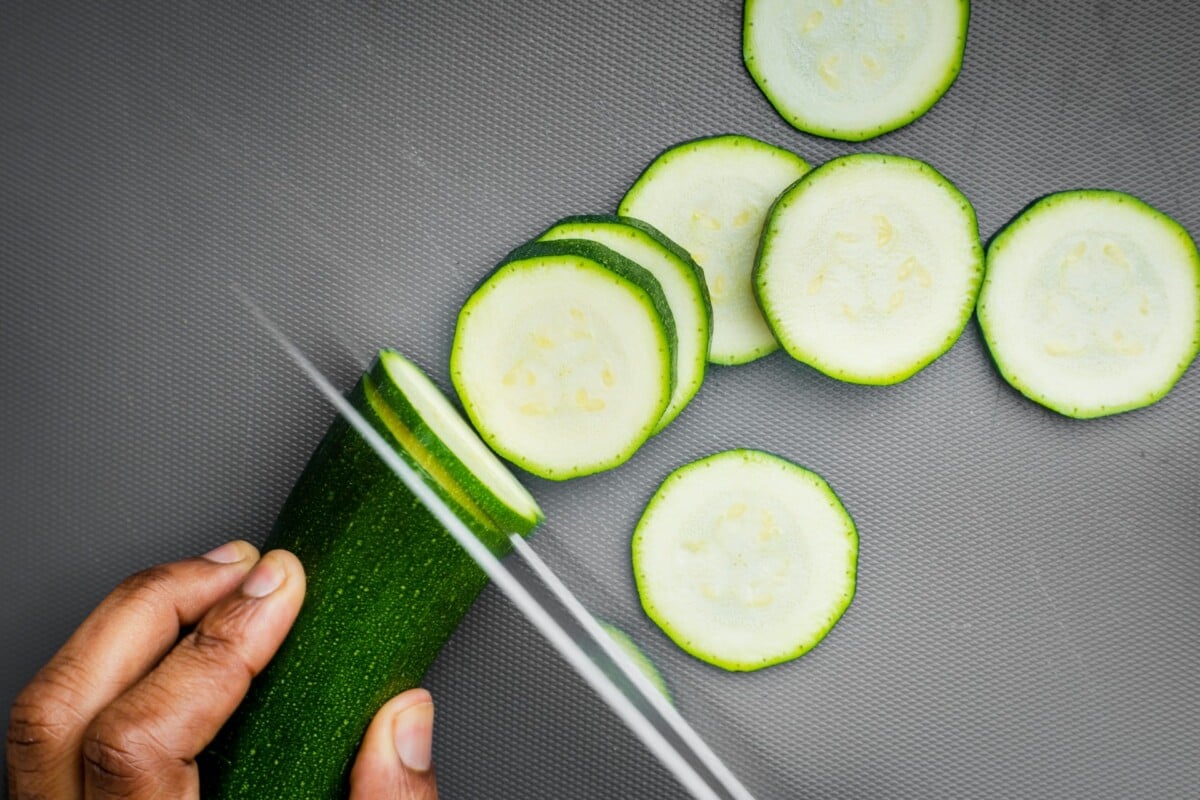 slicing zucchini on gray cutting board