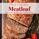 Meatloaf with slices on wood cutting board with fresh herbs and grape tomatoes.