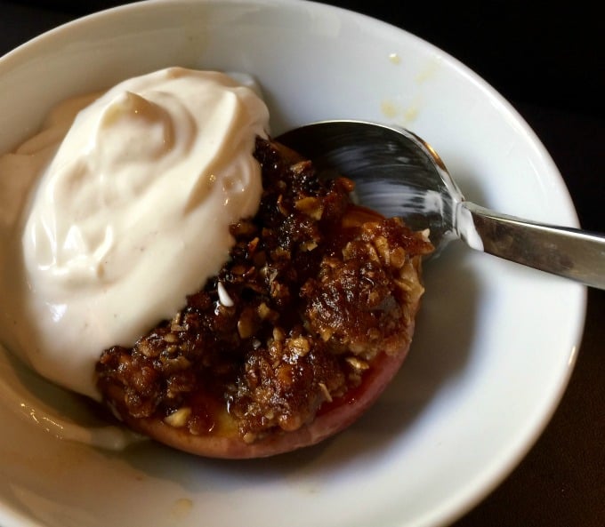 Healthy baked apple with greek yogurt in small white bowl.