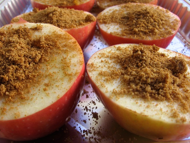 Apples cut in half and topped with cinnamon in baking pan