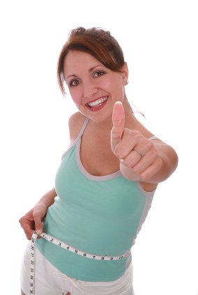 Smiling Woman in Green Tank Top Giving Thumbs Up with Tape Measure Around Her Waist