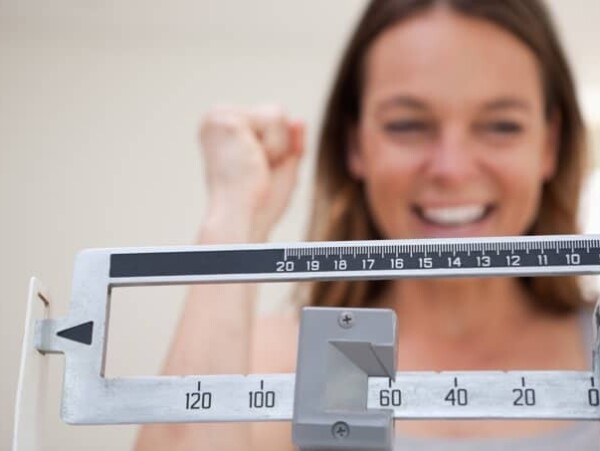 Happy Smiling Woman Standing On Scale Showing Weight Loss