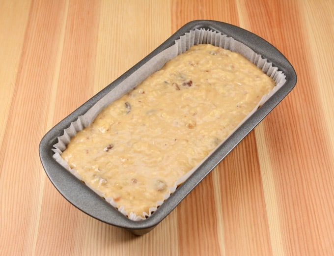 Banana bread batter in a loaf pan on a wooden table