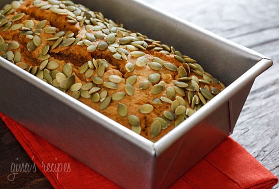 Loaf of pumpkin bread topped with pepitas in baking pan