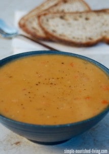 Slow Cooker Yellow Split Pea Soup in blue bowl with sliced bread in the background