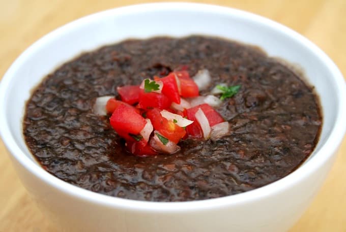 Delicious Black Bean Soup in a White Bowl topped with Pico de Gallo.