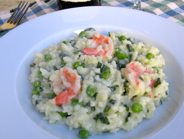 Shrimp Risotto with peas and spinach on white plate with fork.