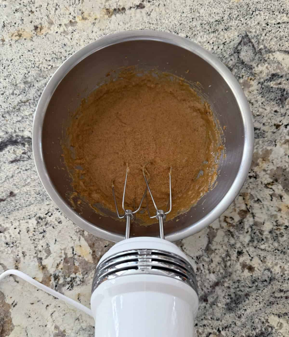 Beating Grapenuts Breakfast Cookie batter in a mixing bowl with a handheld electric mixer.