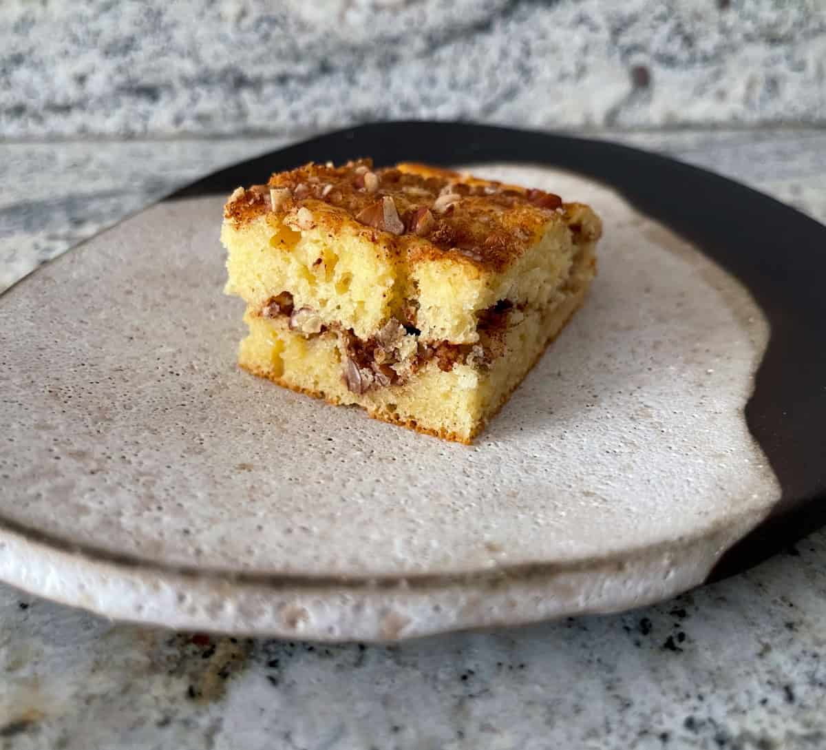 Piece of cinnamon streusel coffeecake on small ceramic plate.