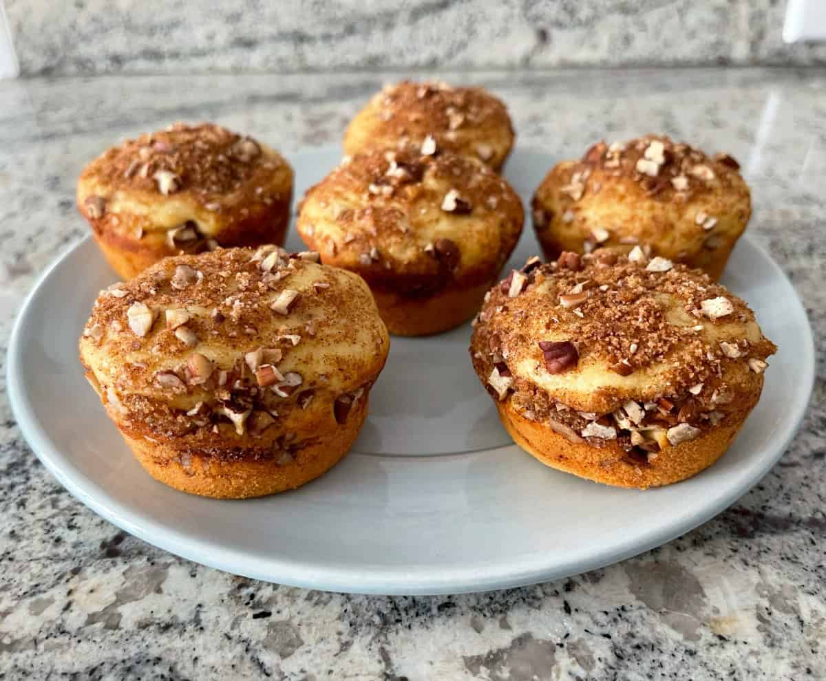 Six cinnamon streusel muffins on small round blue serving plate.