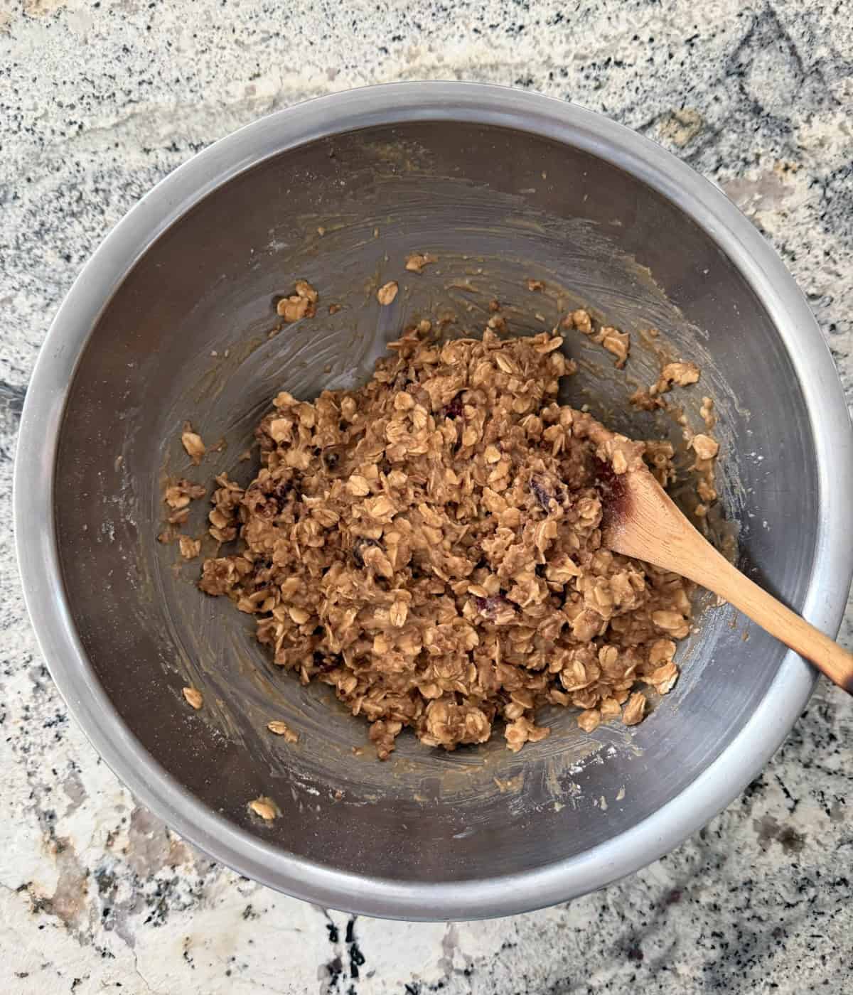 Stirring Grape Nuts Breakfast Cookies with a wooden spoon in a mixing bowl.