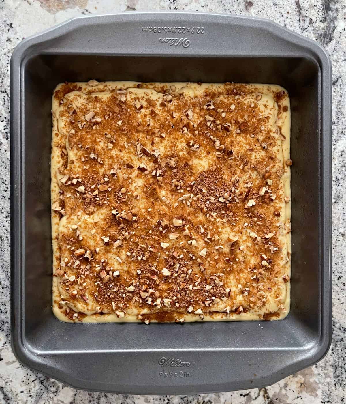 Unbaked cinnamon streusel coffee cake in square baking pan.