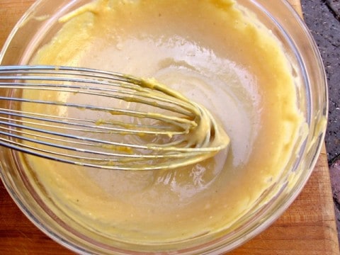 Mixing sweet white miso paste with tahini in small glass bowl with whisk.