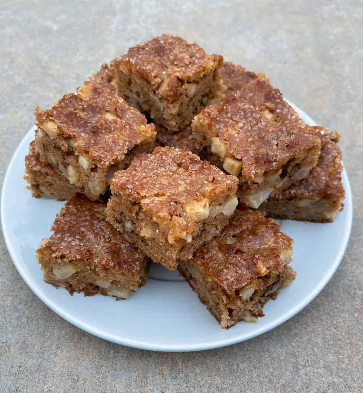 Fresh baked Apple Brownie Nut Bars stacked on a small blue serving plate.