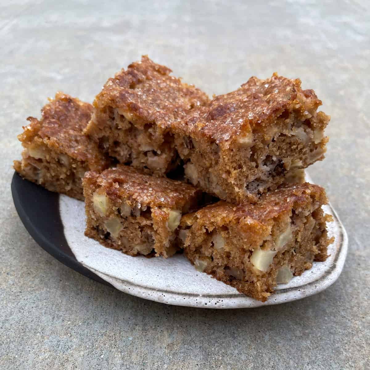 Apple Brownie Dessert Bars stacked on ceramic serving plate.