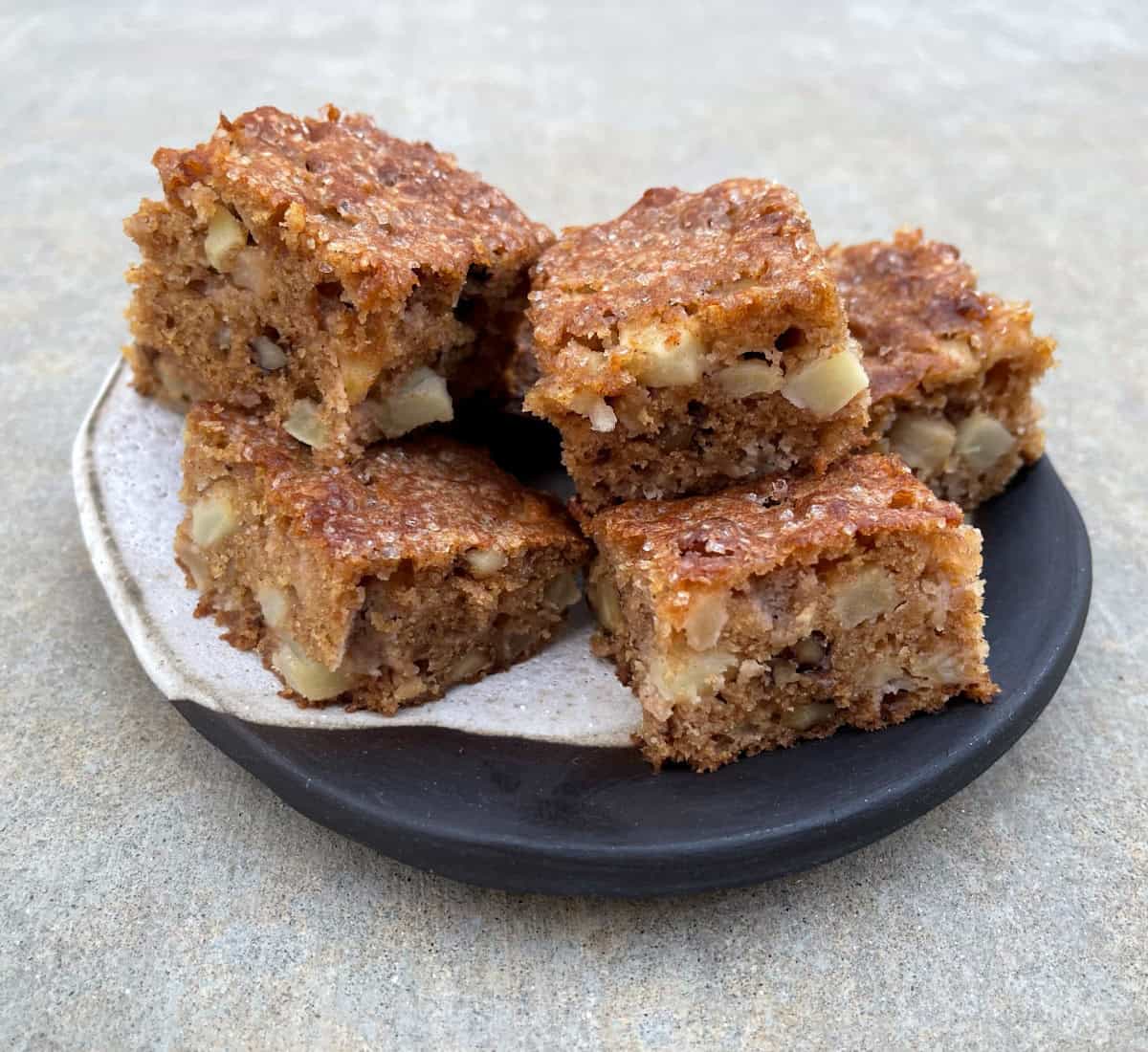Apple Brownie Nut Bars stacked on ceramic serving plate.