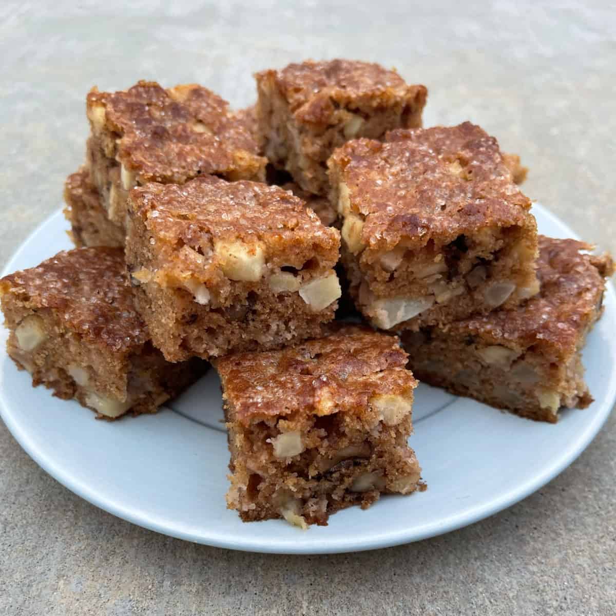 Apple Brownie Nut Squares stacked on round blue plate.