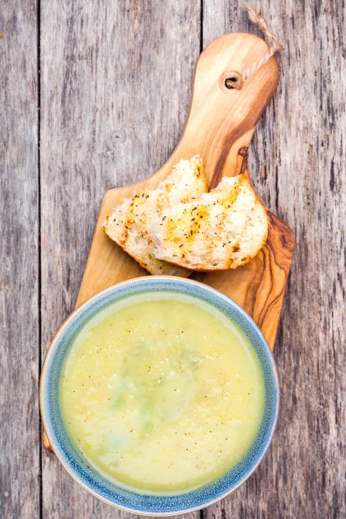 Bowl of artichoke soup with toasted ciabatta on a wood cutting board
