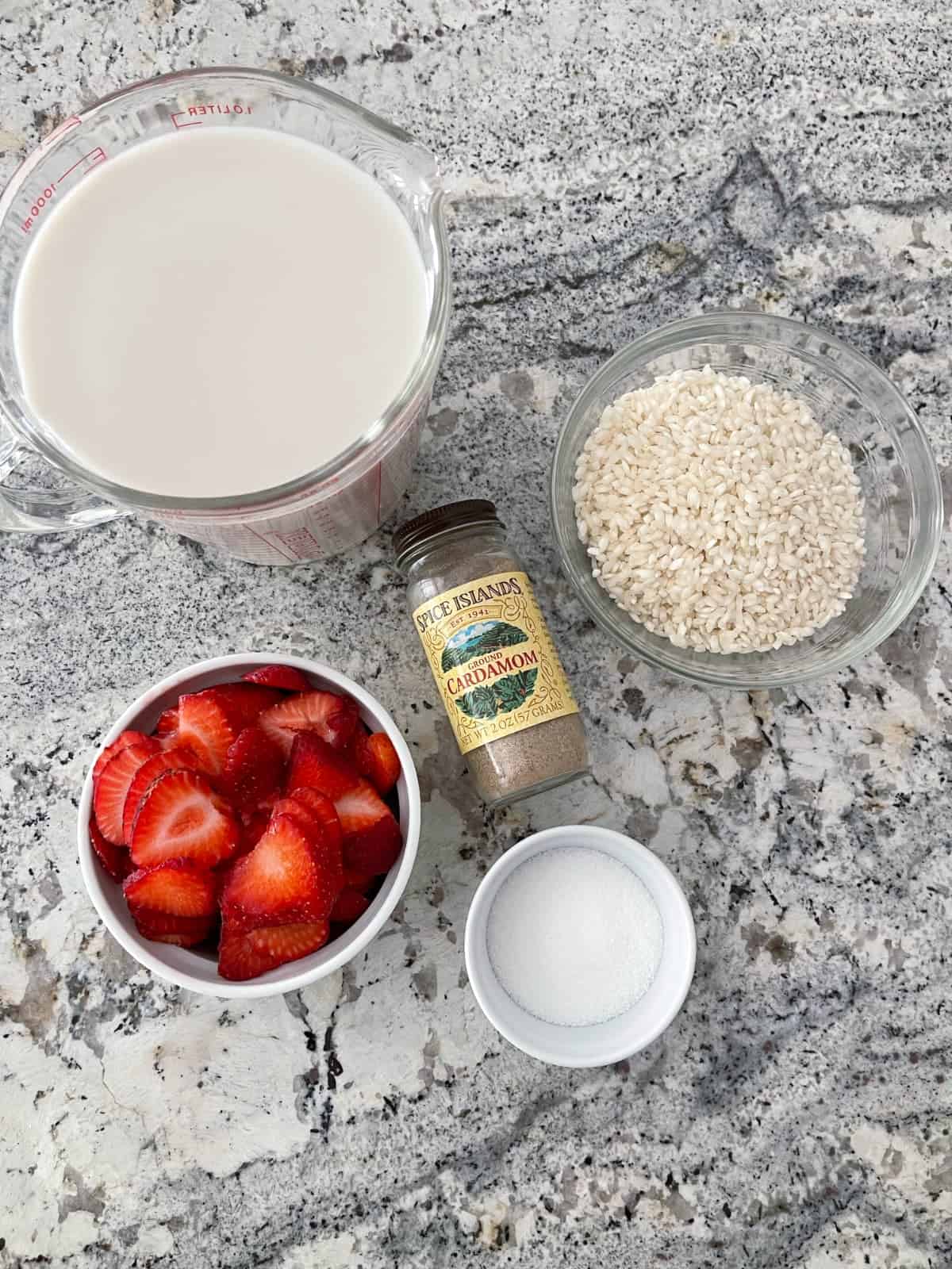 Ingredients including milk, sliced strawberries, Arborio rice, Truvia Baking Blend and ground cardamon.
