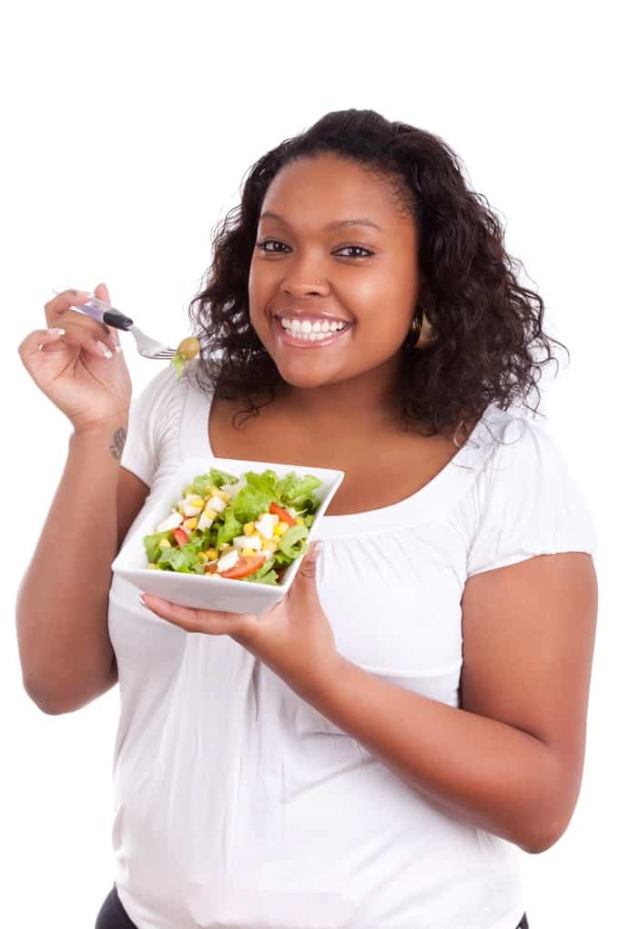 Young woman eating fresh green salad