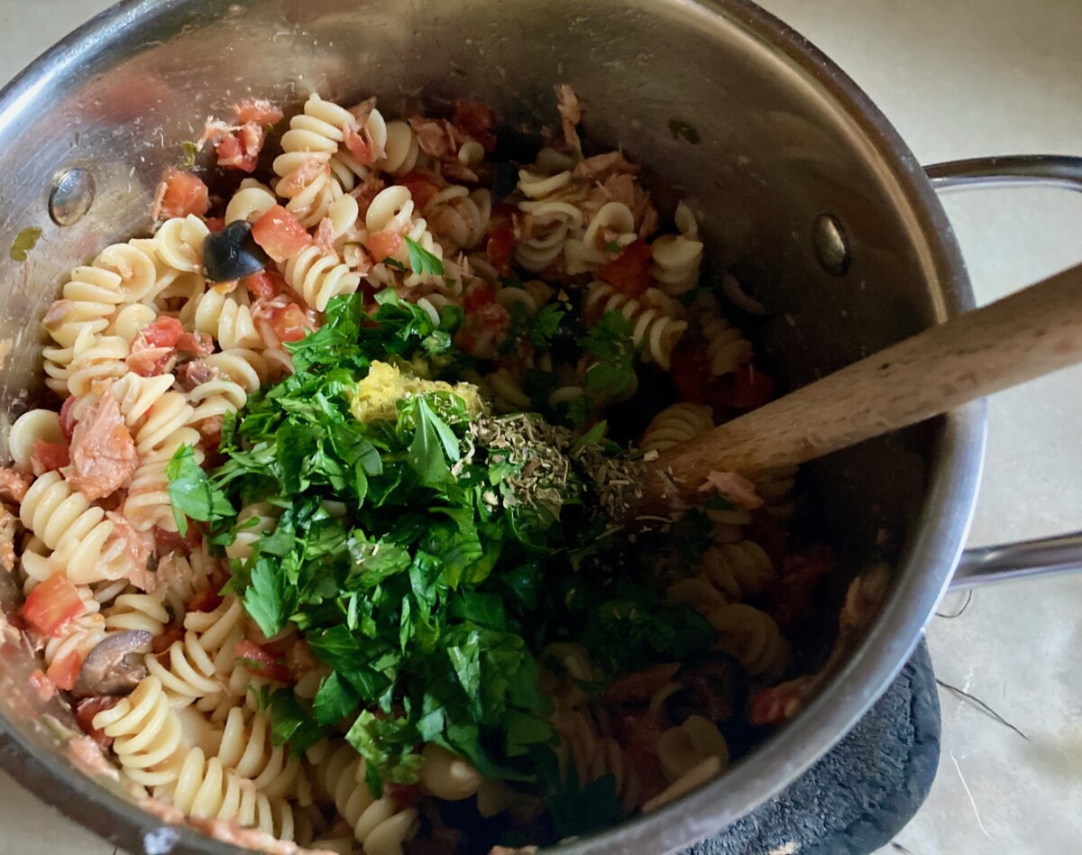 Adding fresh herbs to pasta in stock pot.