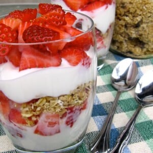 Strawberry, yogurt and granola parfaits in clear glasses on checked tablecloth