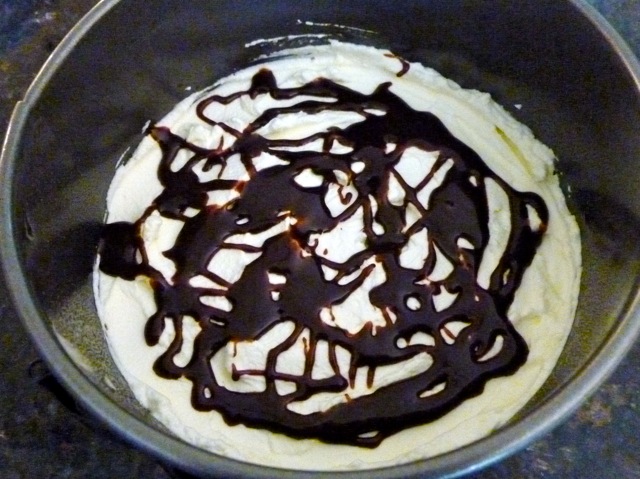 Whipped cream in mixing bowl drizzled with mint chocolate sauce.