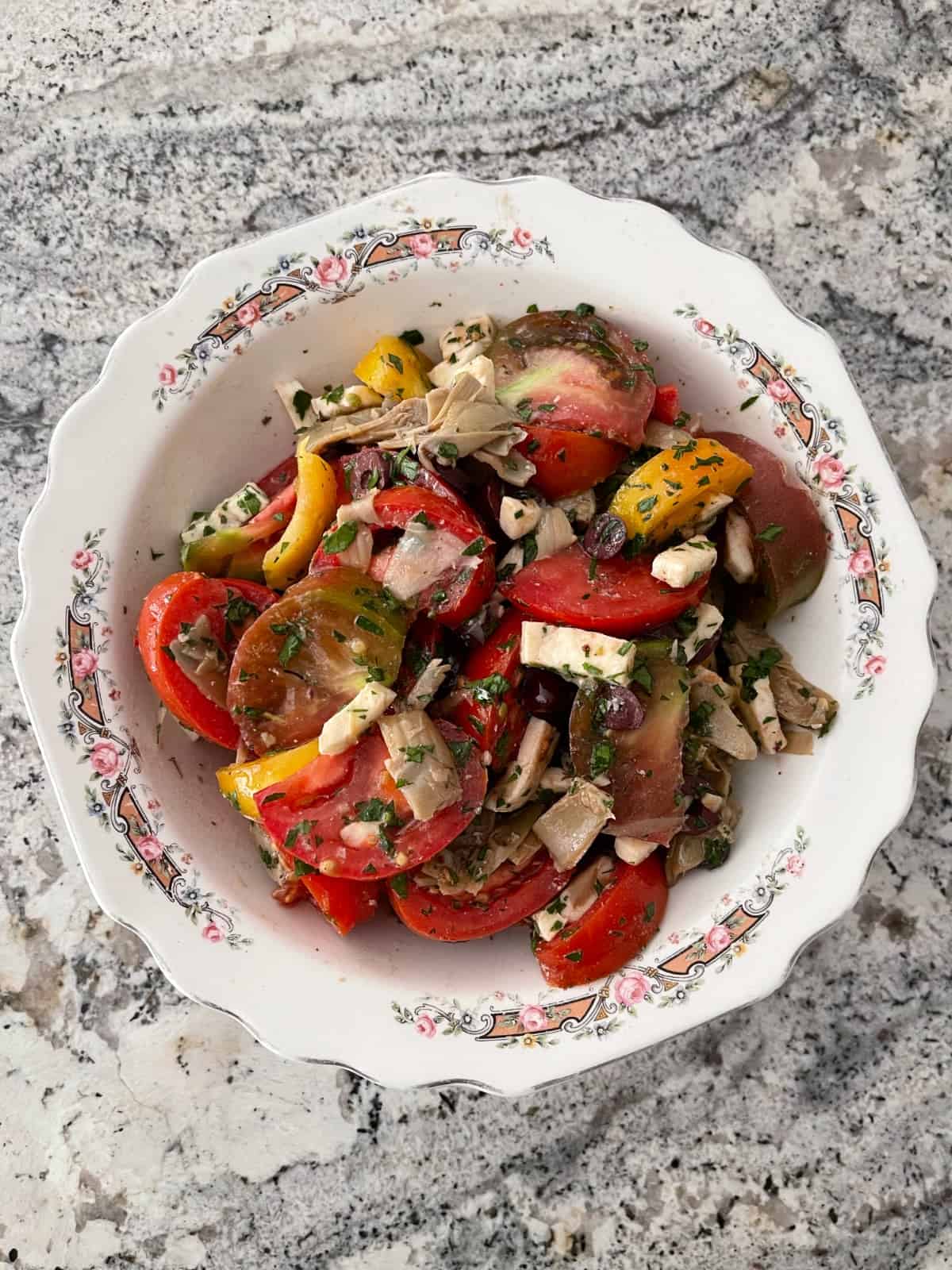 Artichoke tomato salad with mozzarella in white bowl.