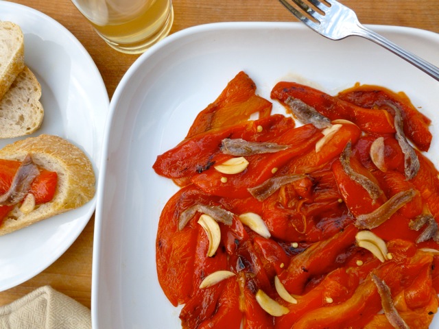 Roasted Red Peppers with Anchovies on white plate with fork from above.