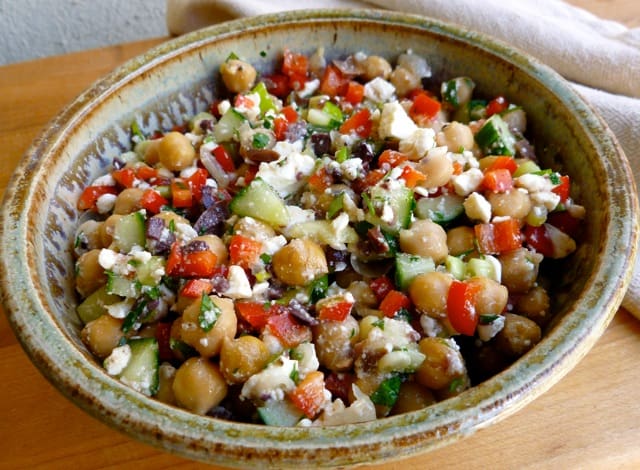 Chickpea & feta salad in pottery bowl on wood board