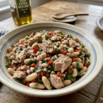 pottery bowl of italian tuna white bean salad with bottle of olive oil in background