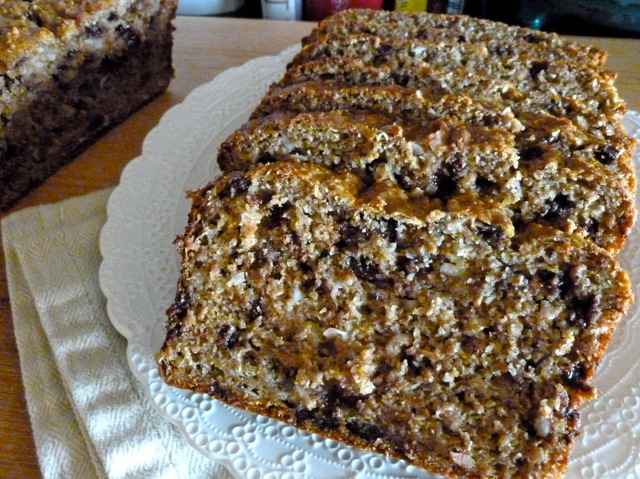 A Loaf of Bran Banana Coconut Chocolate Chip Bread with two slices and small dish of chocolate chips