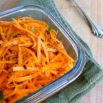 Square glass container of shredded French carrot salad o a green napkin